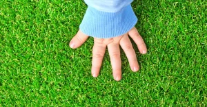 A child's hand resting on green grass