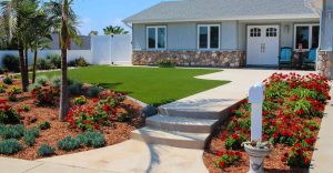 Front yard with flowers, lawn, steps, and a house with a stone facade