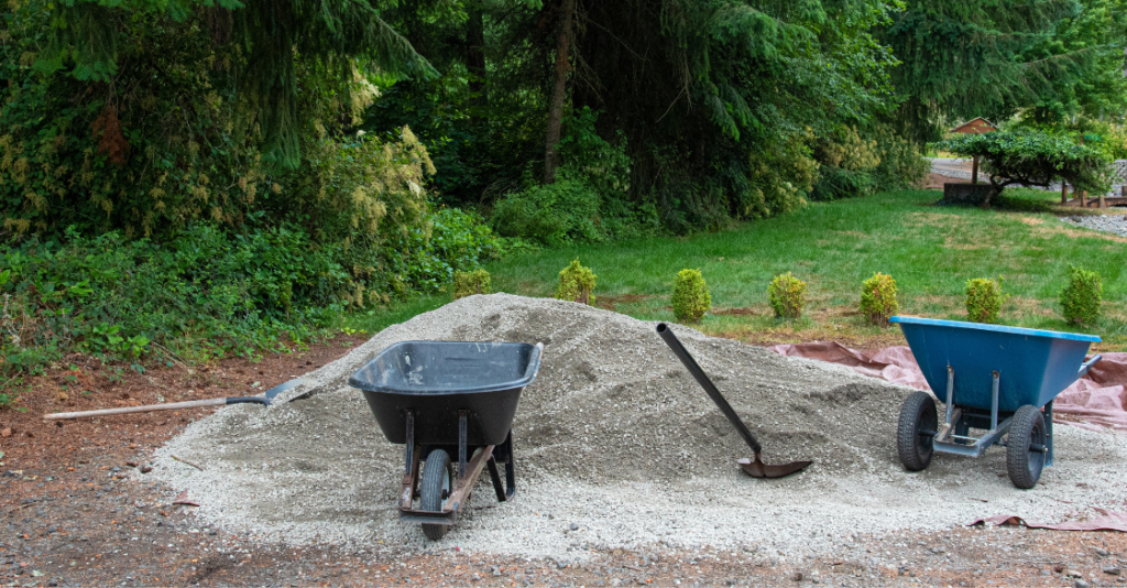 wheelbarrow and shovel sitting on a pile of dirt in a backyard