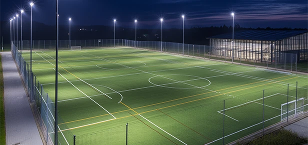 Illuminated soccer field at night with goalposts and surrounding fence