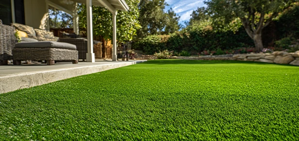 Artificial grass on a lawn with a patio and trees in the background