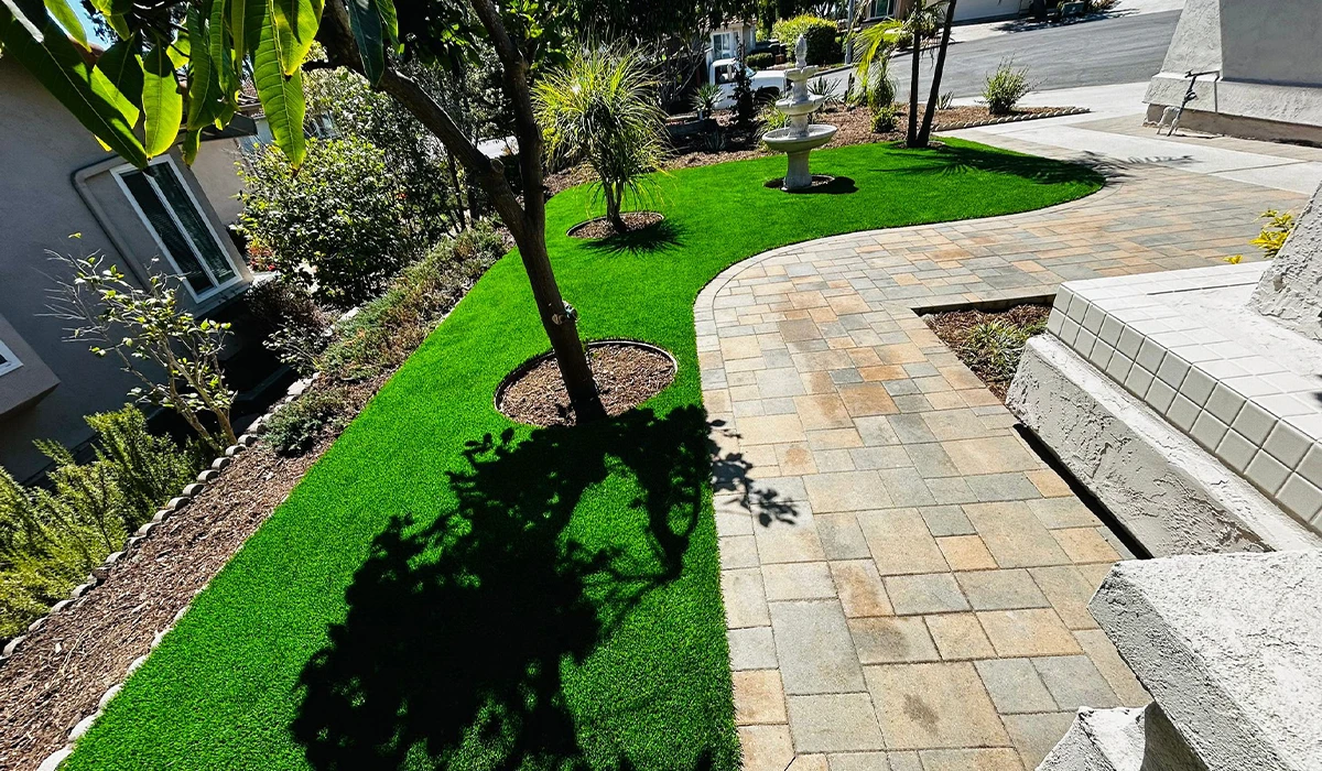 A landscaped area with green grass, stone pathway, and trees