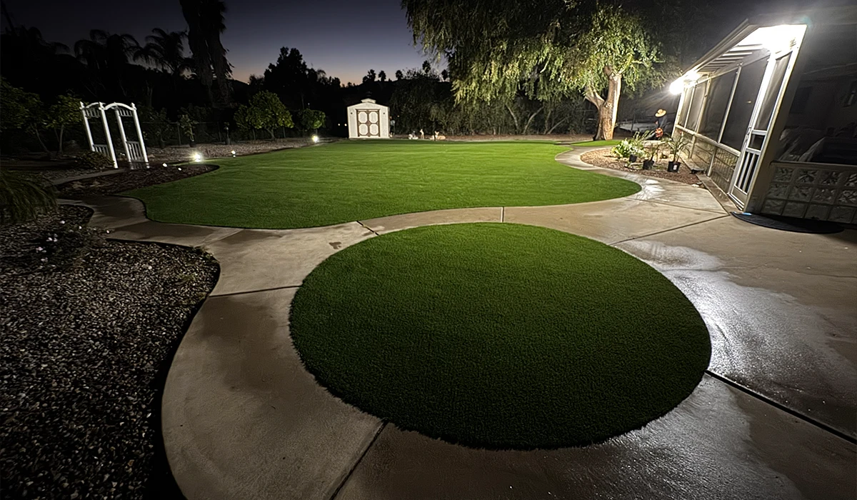 A well-manicured lawn with circular and pathway shapes, illuminated at night