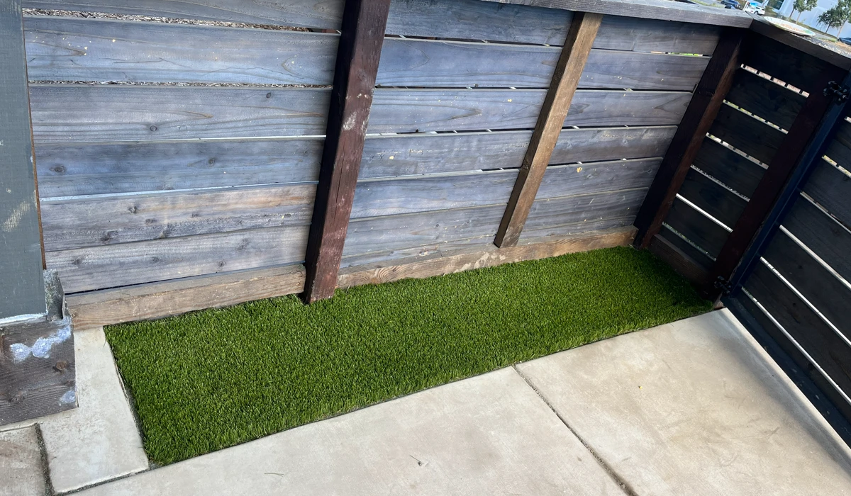 Artificial grass in a narrow outdoor space between wooden fences