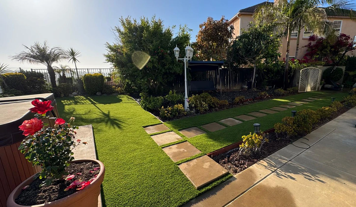 A landscaped garden with pathways, plants, and a house in the background