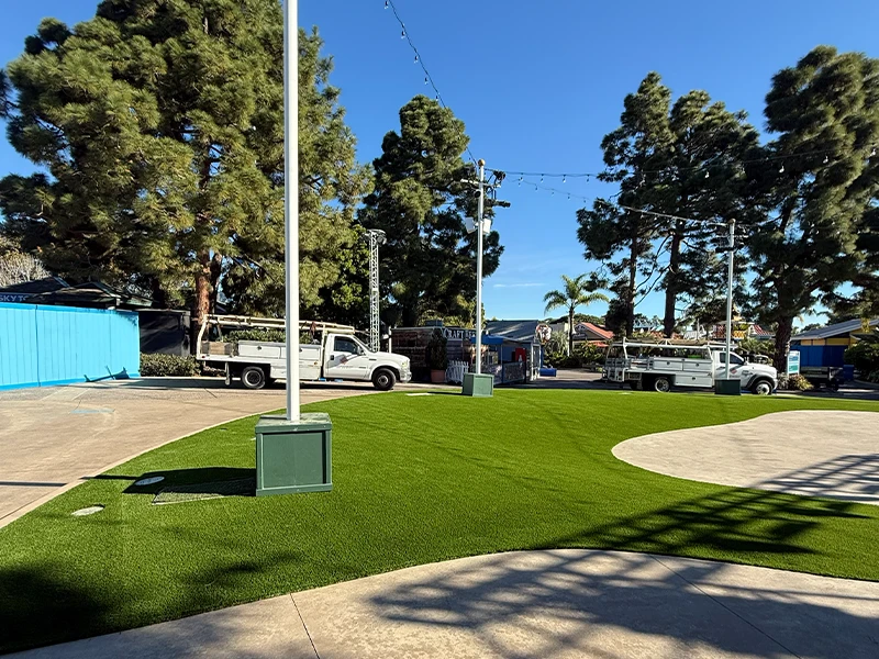 Two service trucks parked on a lawn area with trees and a blue building in the background