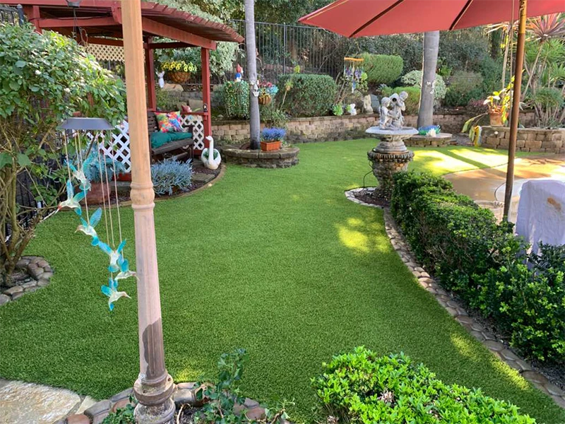Garden scene with green grass, bushes, a gazebo, and an umbrella