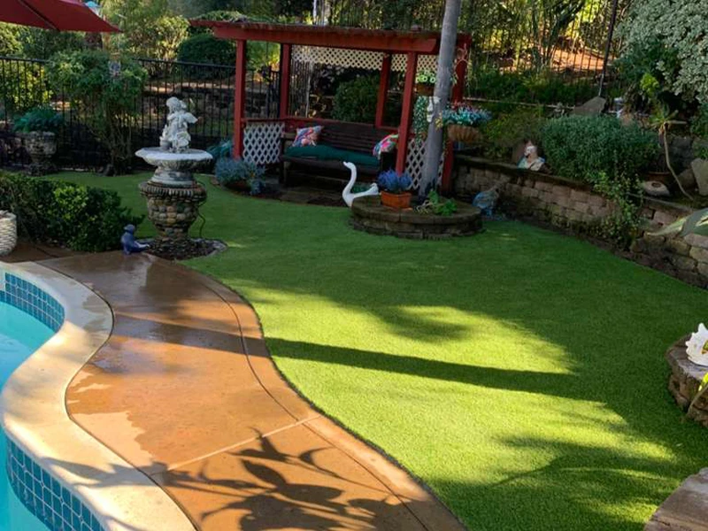 Garden with green grass, a stone path, a fountain, and a gazebo with seating