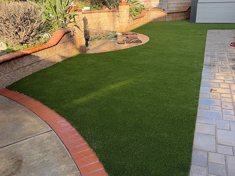Green lawn with brick edging and a small fountain in a landscaped yard