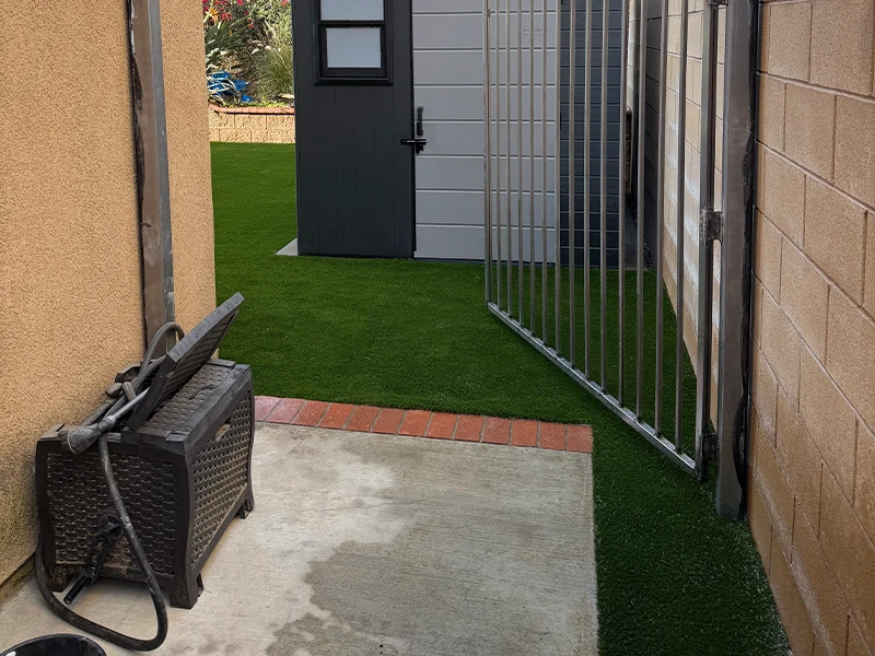 View of a pathway between two walls, leading to a gate and a gray door